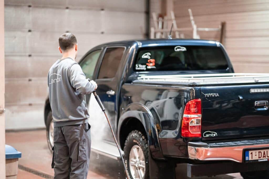 Technicien du garage Incar Motor Houffalize qui nettoie une Toyota après une réparation carrosserie de voiture