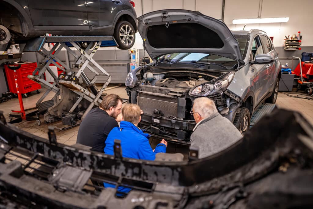 quipe de mécaniciens du garage Incar Motor à Angleur inspectant un véhicule dans l'atelier pour un entretien ou une réparation.